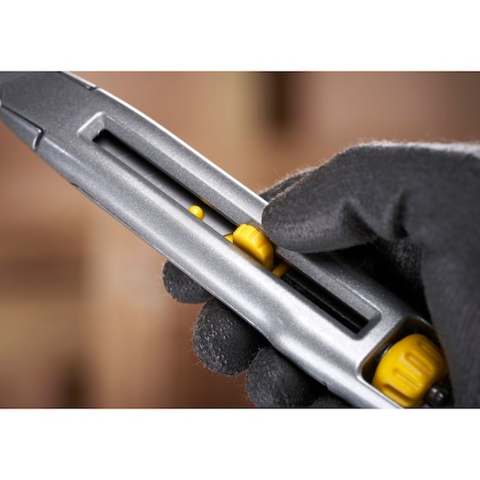 STANLEY 0-10-018 hobbymes close-up met gele schuifknop en een gehandschoende hand die het gereedschap vasthoudt.