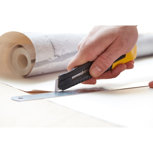 STANLEY 0-10-151 mes snijdt behang met liniaal, close-up foto, hand houdt gereedschap.