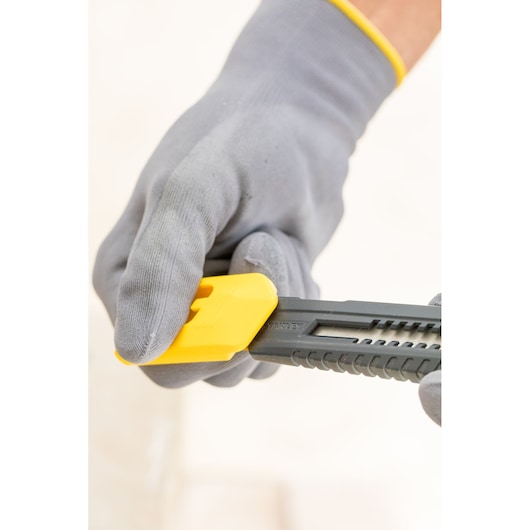 STANLEY 0-10-151 hobbymes met gele schuifknop, vastgehouden door een gehandschoende hand, zijaanzicht close-up.
