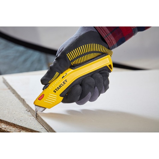STANLEY 0-10-237 hobbymes snijdt gipsplaat, close-up, vastgehouden door een gehandschoende hand.