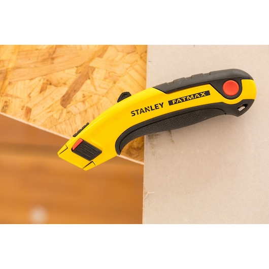Cutter STANLEY 0-10-778 jaune et noir avec poignée ergonomique sur un bord, vue latérale.