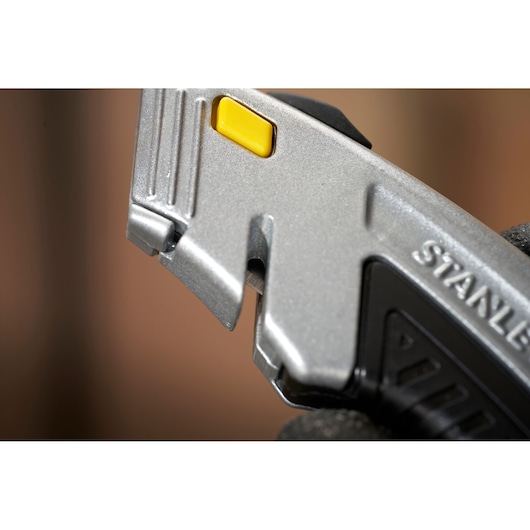 STANLEY 0-10-788 couteau utilitaire gros plan montrant la lame et le bouton jaune.