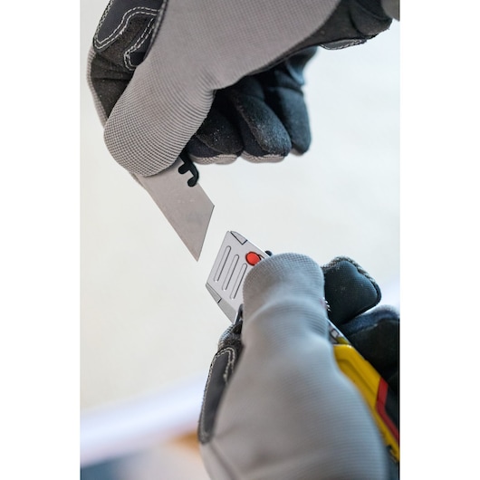STANLEY 0-10-825 remplacement de lame de couteau utilitaire présenté avec des mains gantées, photo en gros plan.
