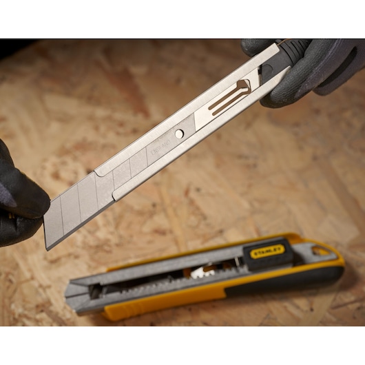 STANLEY 0-11-325 couteau utilitaire à lame cassable avec lame de rechange segmentée sur surface de travail.