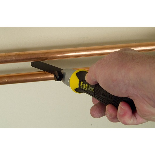 STANLEY 0-20-220 FatMax handzaag snijdt koperen buis, close-up foto met ergonomisch handvat.