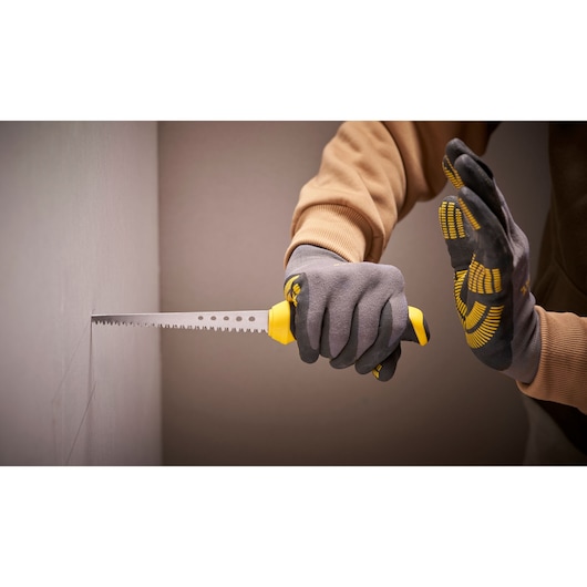 Foto van STANLEY 0-20-556 gipszaag gebruikt door handschoenhanden voor het snijden van gipsplaten, zijaanzicht.