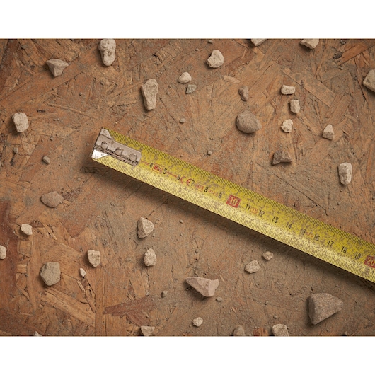 STANLEY 0-30-457 gele rolmaat op ruw hout met verspreide kleine stenen, bovenaanzicht.