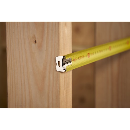 STANLEY 0-30-457 rolmaat op hout, close-up, gele band met zwarte en rode markeringen.