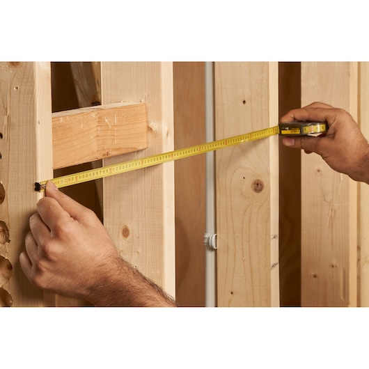 STANLEY 0-32-125 rolmaat meet houten frame, close-up foto van product in gebruik.