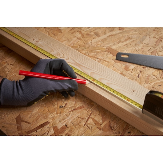 STANLEY 0-32-125 rolmaat gebruikt om hout af te tekenen met rode potlood, close-up op werkbank.