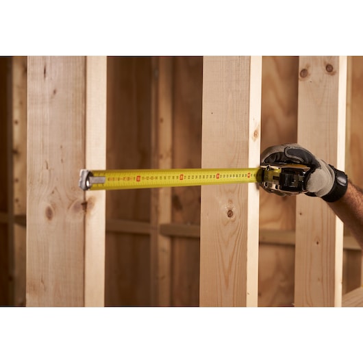 STANLEY 0-33-195 rolmaat tegen houten balken, close-up tijdens bouw.