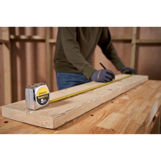 STANLEY 0-33-195 rolmaat op houten plank, persoon markeert afmetingen in werkplaats.