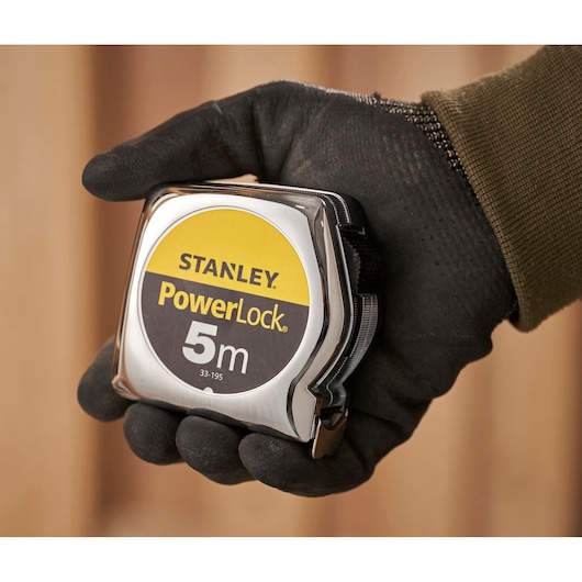 STANLEY 0-33-195 rolmaat in een gehandschoende hand, PowerLock 5m, close-up fotografie.