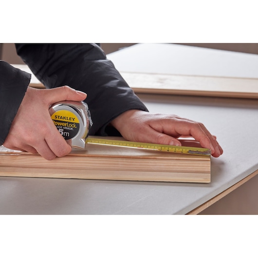 Foto van STANLEY 0-33-514 rolmaat gebruikt om een houten plank op een tafel te meten.