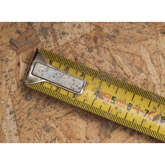STANLEY 0-33-532 gele rolmaat met metalen haak, close-up op vuil multiplex.