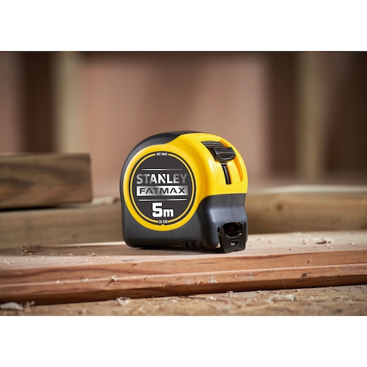 STANLEY 0-33-720 rolmaat, 5m FatMax, zwart en geel omhulsel, op houten planken, fotografie