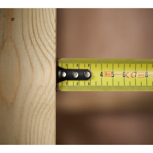 STANLEY 0-33-728 rolmaat close-up op hout, gele kleur met duidelijke metrische markeringen.