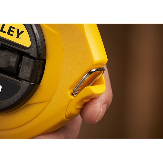 STANLEY 0-34-108 rolmaat close-up met geel omhulsel, metalen haak en hand.