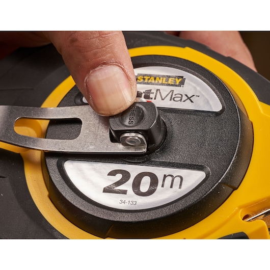 STANLEY 0-34-133 meetlint close-up, geel en zwart omhulsel, vinger op de knop.
