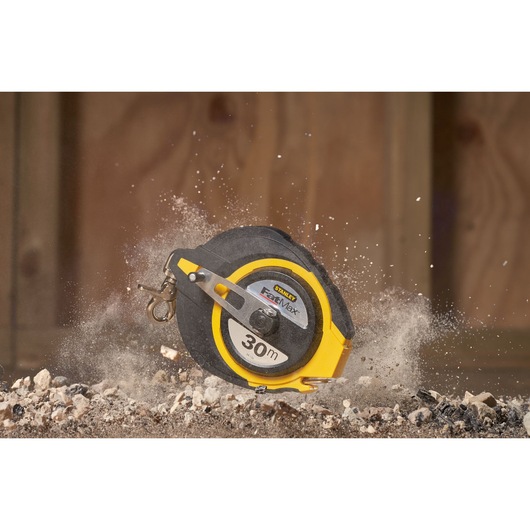 STANLEY 0-34-134 meetlint, 30m, zwart en geel behuizing, gefotografeerd op bouwpuin.