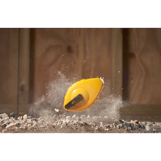 STANLEY 0-47-440 gele krijtlijnhaspel, dynamisch beeld op aarde en stenen, fotografie productopname.