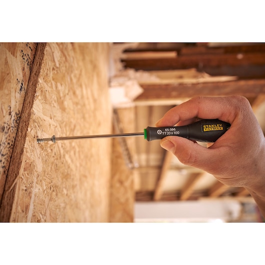 Tournevis Stanley 0-65-396 en utilisation, manche noir avec logo jaune, vissage dans une surface en bois.