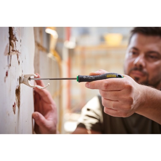 Photo du tournevis STANLEY 0-65-396 utilisé pour fixer un support mural, gros plan sur la main et l’outil en action.