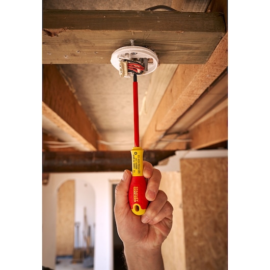 STANLEY 0-65-419 tournevis isolé utilisé pour installer des câbles électriques, tenu en main lors de travaux au plafond.