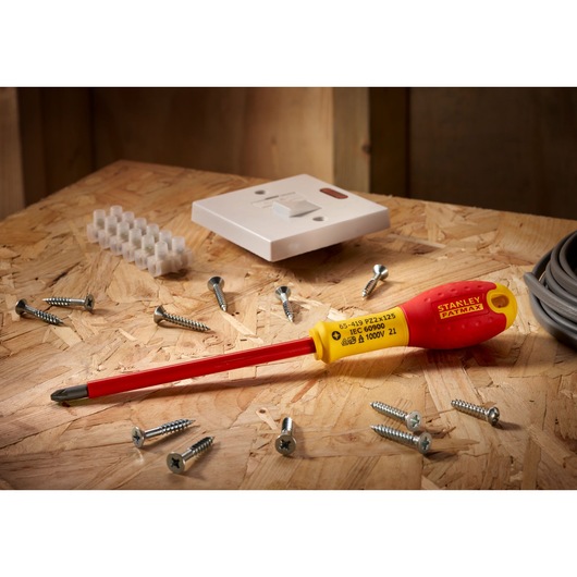 Stanley 0-65-419 tournevis isolé à manche jaune et rouge, présenté sur surface bois avec vis et pièces électriques.