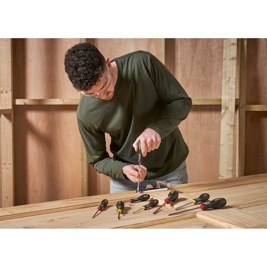 Foto van STANLEY 0-65-437 schroevendraaierset op houten tafel met medewerker in werkplaats.