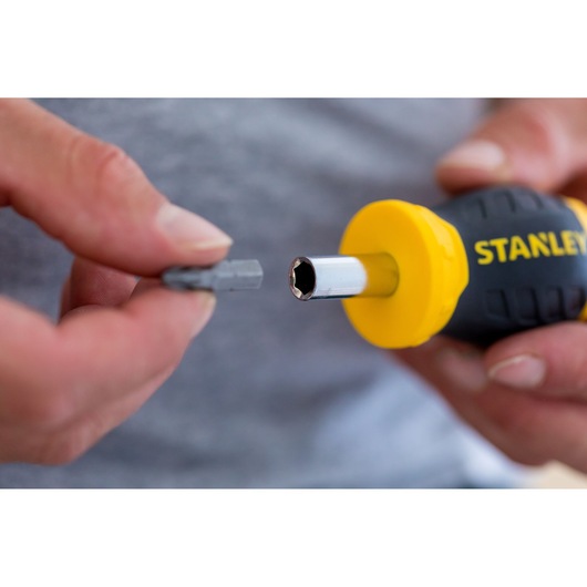 Poignée de tournevis STANLEY 0-66-357 avec accent jaune et embout interchangeable tenu en main, gros plan.