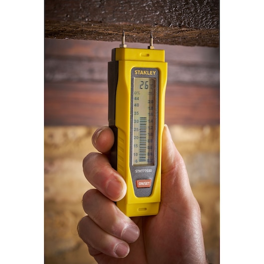 STANLEY 0-77-030 humidimètre appliqué sur du bois, outil portatif jaune, vue de face.