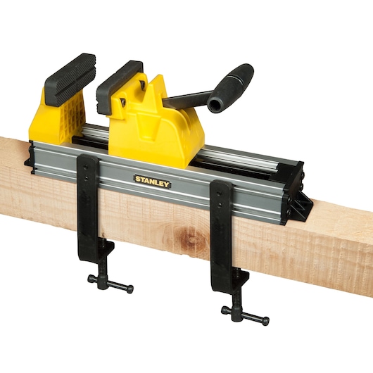 STANLEY 0-83-179 houtbewerkingsklem met gele handgreep en metalen frame, zijaanzicht op houten balk.