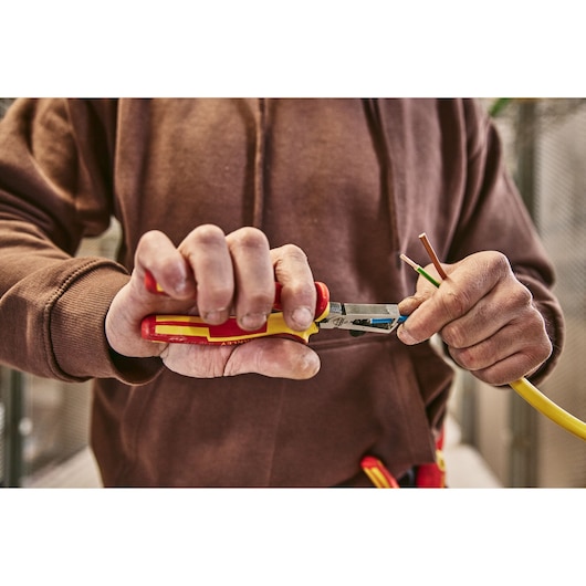Photo d'une personne utilisant une pince isolée STANLEY 0-84-010 pour dénuder un fil électrique.