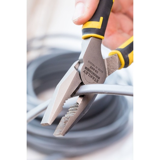 STANLEY 0-89-868 combinatietang met geel-zwarte handgreep knipt een grijze kabel, close-up.