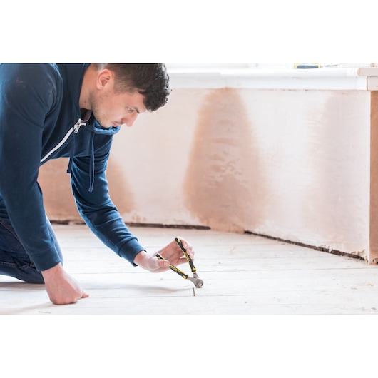 Pince STANLEY 0-89-875 utilisée pour retirer un clou d’un plancher en bois pendant une rénovation.