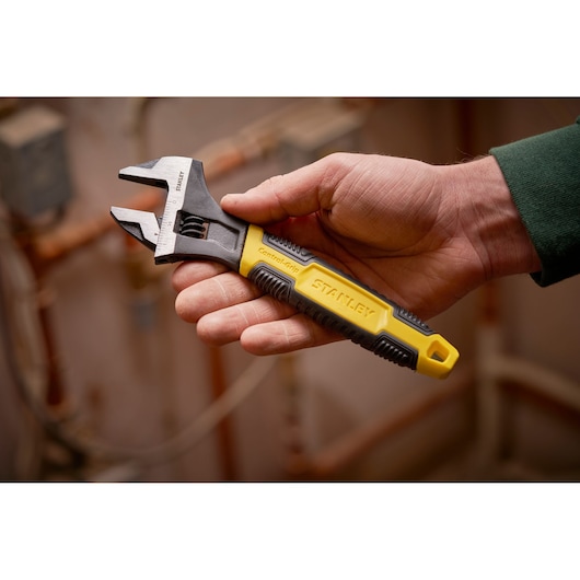 STANLEY 0-90-947 verstelbare moersleutel met geel-zwart ControlGrip-handvat, getoond in hand, binnen.