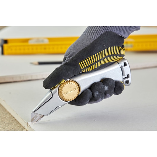 STANLEY 1-10-550 stanleymes met gouden wiel, gehandschoende hand snijdt gipsplaat.