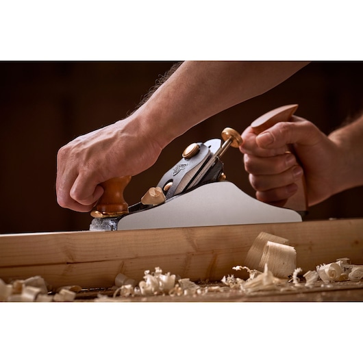 Foto van STANLEY 1-12-136 hand schaaf in gebruik op hout, close-up met houtsnippers.