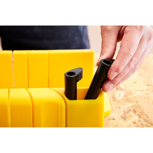 Photographie du STANLEY 1-20-600 boîte à onglets jaune avec une main plaçant un accessoire de scie noir.