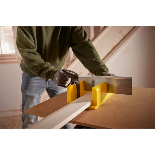STANLEY 1-20-600 scie à main et boîte à onglets jaune utilisées pour couper du bois sur un établi, vue rapprochée.