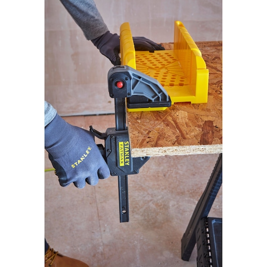 STANLEY 1-20-600 serre-joint tenant un bord de contreplaqué avec guide jaune, gros plan, atelier.