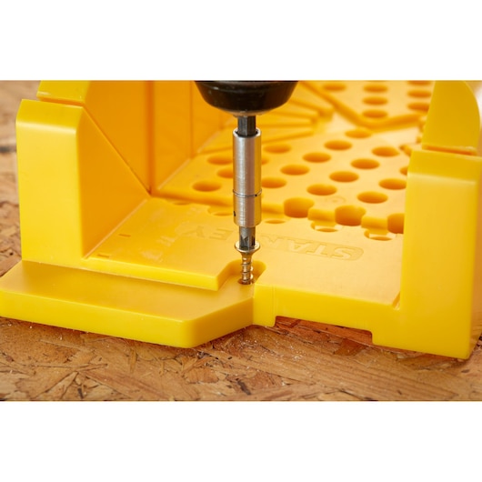 STANLEY 1-20-600 boîte à onglets en plastique jaune avec perceuse en action, angle avant, sur surface en bois.