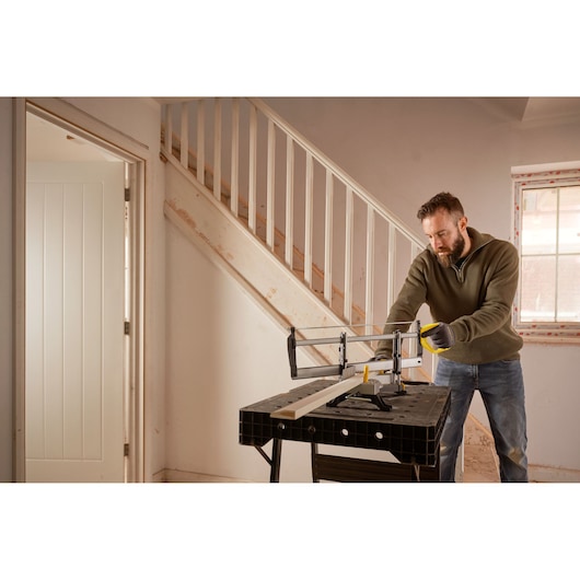 STANLEY 1-20-800 scie à main utilisée sur un établi en intérieur par une personne coupant du bois près d’un escalier.