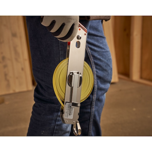 STANLEY 1-34-477 open rolmaat met gele band, vastgehouden door een gehandschoende hand op een bouwplaats.