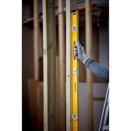 Photo du niveau à bulle STANLEY 1-42-922 utilisé verticalement sur une structure en bois.