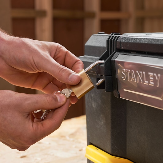 Close-up van STANLEY 1-70-316 gereedschapskist vergrendeld met een messing hangslot en sleutels.