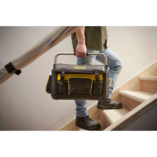 STANLEY 1-79-213 sac à outils noir et jaune, photographie transporté par une personne dans des escaliers.