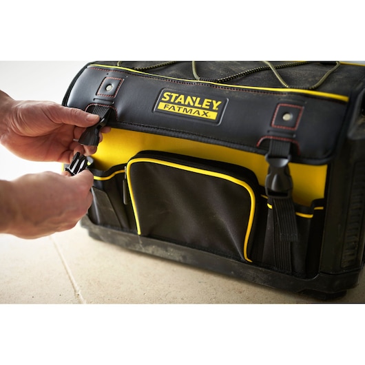Sac à outils STANLEY 1-79-213, noir et jaune, angle avant, mains attachant la boucle latérale.