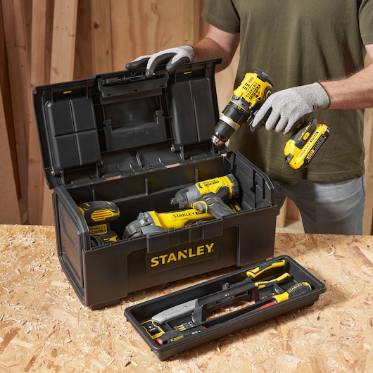 Photo de la boîte à outils STANLEY 1-79-217 avec des outils électriques jaunes et accessoires sur un établi.